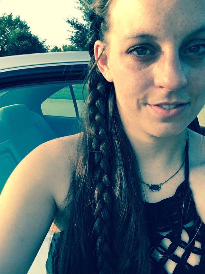 Maegan smiling at the camera, her hair half braided and half straight hanging over her shoulder