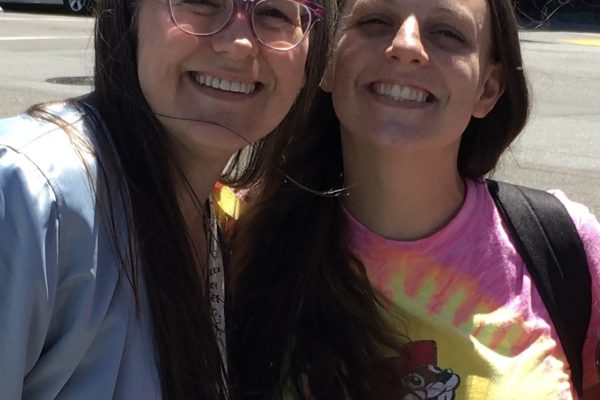 Stacey and Maegan standing on the street corner in San Francisco, the sun shining on their smiling faces